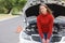 Annoyed young woman beside her broken down car