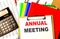 ANNUAL MEETING text written on paper clipboard with chart and calculator