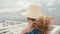 Anonymous blonde woman with long hair and straw hat sitting on upper deck of ferry ship motorboat enjoying freedom and