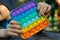 Anonymous child hold in his hands sensory toy pop it and shows it in front of himself.Rainbow color.Antistress toy for children