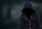 Anonymous Criminal Man in hood in front of dark room