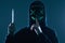 Anonymous criminal man with kitchen knife in a black hoodie and neon mask