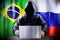 Anonymous hacker working on a laptop, flags of Brazil and Russia