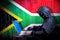 Anonymous hooded hacker, flag of South Africa, binary code - cyber attack concept