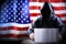 Anonymous hooded hacker, flag of United States of America, binary code - cyber attack concept