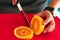 Anonymous man cutting an orange at home. Close-up photo