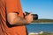 Anonymous man holding DSLR camera in hands next to seashore, no face, body detail