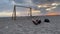 Anonymous man lying on sand near football gates at sunset. Beautiful sky at dusk for a tired traveler. Film grain. Soft