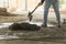 An anonymous man mixes a batch of concrete on the bare floor of a building under construction