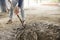 An anonymous man mixes a batch of concrete with a shovel. Manual construction labor.