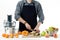 Anonymous man wearing an apron, preparing healthy freshly made fruit juice, using modern electric juicer, healthy lifestyle concep