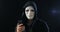 Anonymous masked fraudster in hood demands a ransom for blackmail using a smartphone. Masked Criminal intimidates the