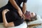 Anonymous osteopath treating neck of female patient on stretcher