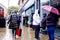 Anonymous Shoppers Or People Sheltering Under Umbrellas During Heavy Rain