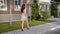 Anonymous trendy brunette in dress and high heels walking confidently along street in summertime.