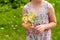 Anonymous unrecognizable elementary school age child holding a bunch of colorful field flowers and herbs in hands, closeup