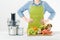 Anonymous woman wearing an apron, ready to start preparing healthy fruit juice using modern electric juicer, healthy lifestyle con