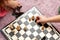 Anonymous young school age children playing chess at home, board on the floor, hands closeup, moving chess pieces. Chessboard top