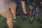 An anonymous young woman picks up a hex dumbbell lying on an artificial grass mat with other free weights. Working out at the gym