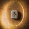 Ansuz. Handmade scandinavian wooden runes on a wooden vintage background in a circle of light. Concept of fortune