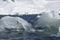 Antarctic iceberg with Shore covered with snow in the background