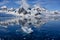 Antarctic landscape with snow covered mountains, glacier, dark blue sea with ice floes and reflections, Paradise Bay