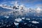 Antarctic landscape with snow covered mountains, glacier, dark blue sea with ice floes and reflections, Paradise Bay