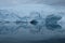 Antarctica glaciers reflect in mirror blue bay on cloudy day