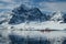 Antarctica orange and red kayaks in a mirror blue bay beneath snow capped mountains