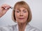 Anti-aging beauty cosmetics. Sensual mature woman applying rejuvenating serum onto face, light blue studio background