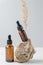 Anti aging serum with collagen and peptides in dark glass bottles with dropper on gray background with natural stone and dry