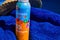 Anti-sunburn spray on a blue towel by a swimming pool