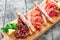 Antipasto platter cold meat plate with grissini bread sticks, prosciutto, slices ham, beef jerky, salami and arugula