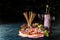 Antipasto platter with ham, prosciutto, salami, blue cheese, mozzarella, olives, grissini bread sticks with pesto