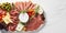 Antipasto platter with prosciutto crudo or jamon, parmesan cheese, olives and tomatoes on white marble background, top view