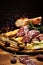 Antipasto various appetizer. Cutting board with salami, cheese, bread and olives on dark wooden background