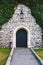 Antique arched wrought-iron doors in an old stone fortress wall using green lush ivy. Beautiful antique frnar over the old door