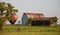 Antique barn in a field with a colorful hot air balloon