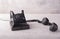 Antique black telephone with off-hook for a call, on a wooden table with white shabby paint.