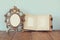Antique blank victorian style frame and old open photograph album on wooden table. retro filtered image