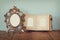 Antique blank victorian style frame and old open photograph album on wooden table. retro filtered image.