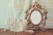 Antique blank victorian style frame, perfume bottle and white pearls on wooden table. retro filtered and toned