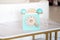 An antique blue turquoise and white rotary home phone toy made of wood rests on a white marble patterned shelf for Kidâ€™s