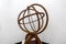 Antique brass armillary sphere on a wooden stand on white background. ancient scheme of the movement of celestial stars