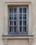 Antique broken wooden window on old brick building with green decrepit ornamented facade