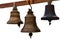 Antique bronze bells hang on a wooden beam, isolated on white background.