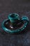 Antique ceramic candlestick of turquoise color on gray cement background, ancient object designed for candles representing