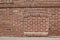 Antique clay exterior brick wall background with bricked in basement windows along a sidewalk