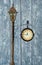 Antique clock on a pole with a lantern. On a wooden gray background.