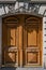 Antique double door entrance of old building in Paris France. Vintage wooden door panel and stone fretwork relievo details above.